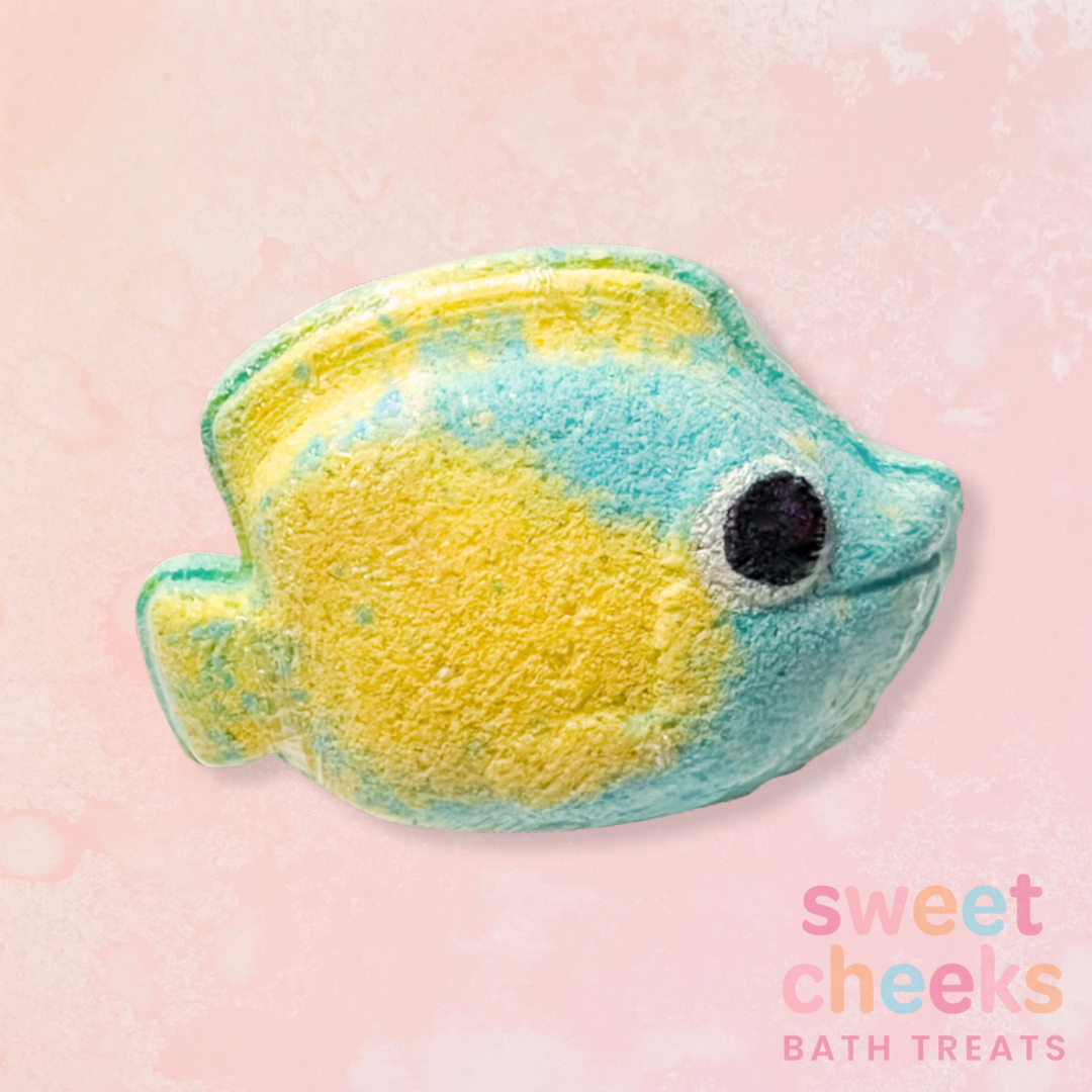 Fish-shaped bath bomb with 'sweet cheeks bath treats' branding on a pink background