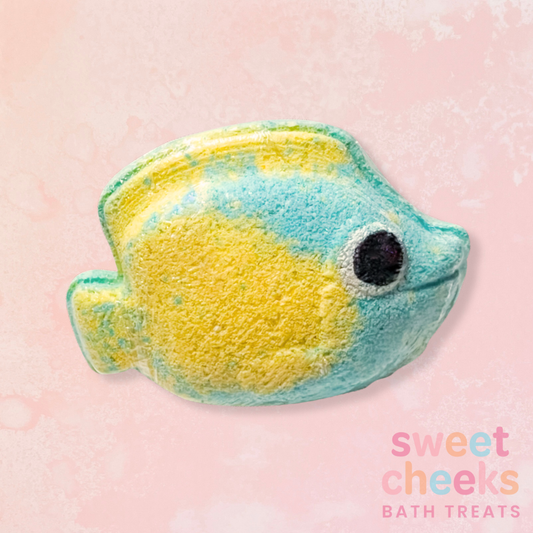 Fish-shaped bath bomb with 'sweet cheeks bath treats' branding on a pink background