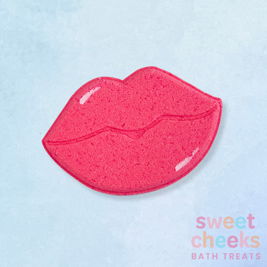 Pink lip-shaped bath bomb on a light blue background with 'sweet cheeks bath treats' text.